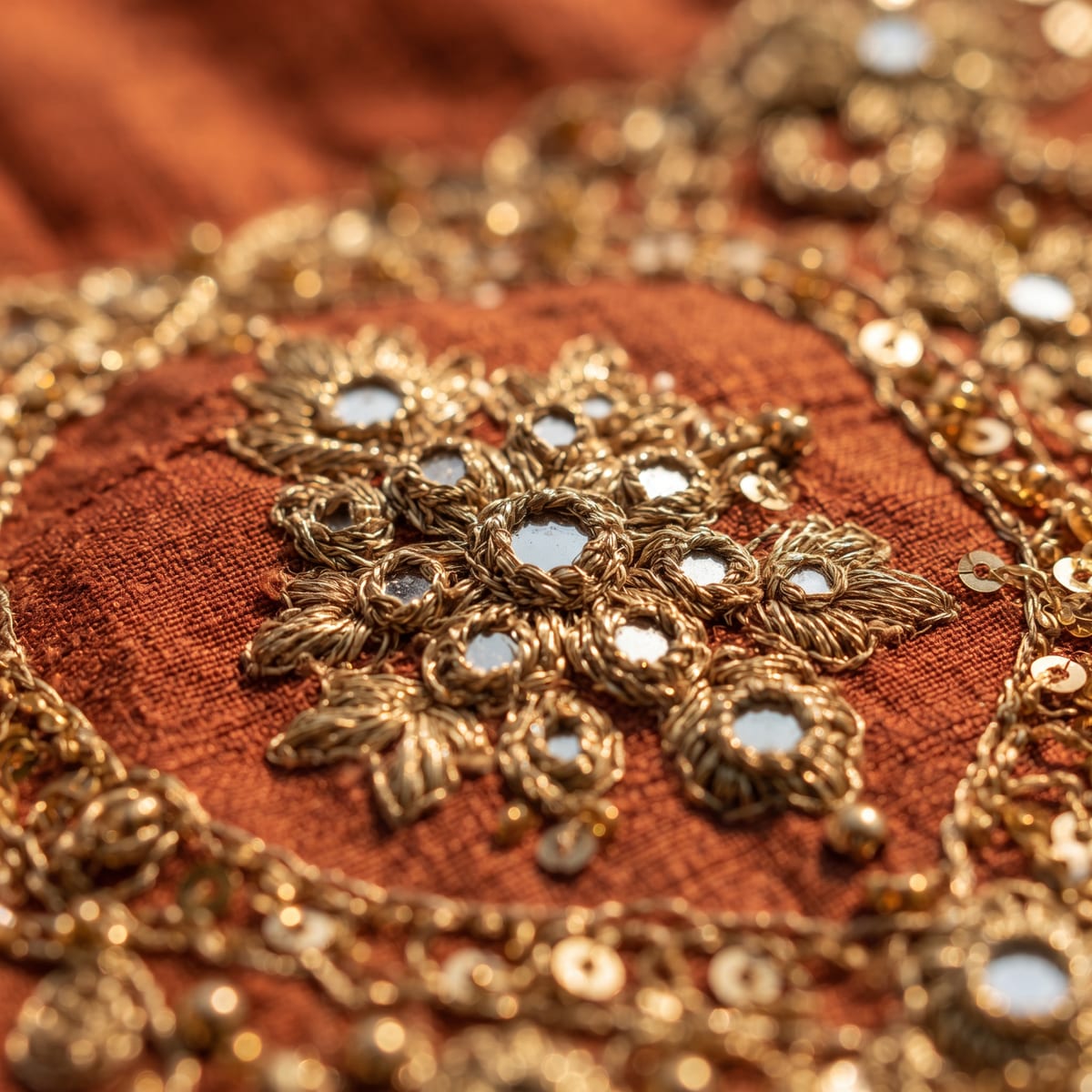 Macro of gold zari embroidery on rust silk